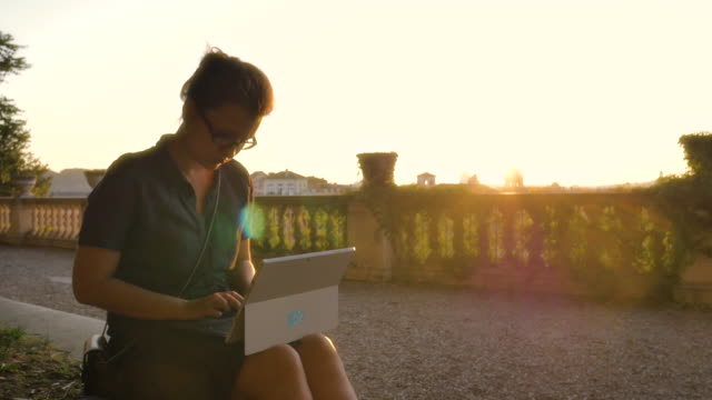 Schöne-junge-Frau-Student-auf-hohen-Balkon-im-Campidoglio-schreiben-arbeiten-auf-Laptop-Computer-vor-Rom-Stadtbild-bei-Sonnenuntergang-betrachten-historische-Gebäude-und-Kuppeln-Zeitlupe-steadycam
