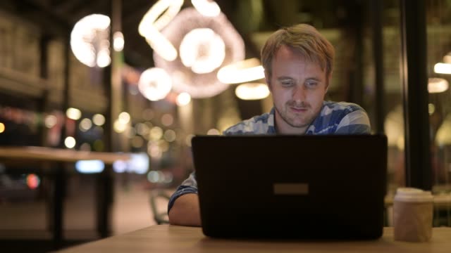 Hombre-de-negocios-guapo-beber-café-durante-el-uso-de-laptop-en-la-noche