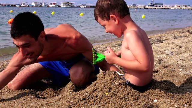 Young-father-with-a-small-son-on-a-sea-beach,-Greece