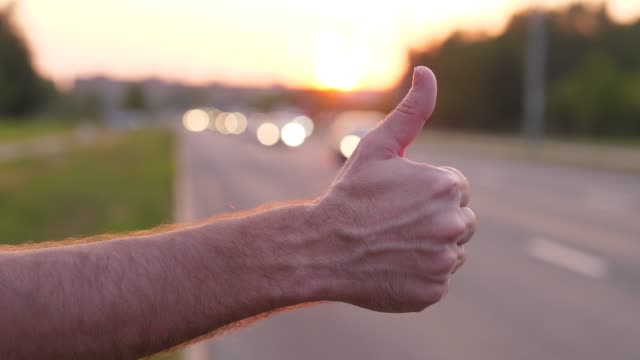 Man-hand-close-up-thumb-up,-hitchhiker-on-road-try-to-catch-car