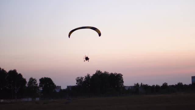 Der-Pilot-auf-einem-Gleitschirm-fliegt-in-den-Himmel-über-Sonnenuntergang-und-Nacht-Landschaft.-Hintergrund