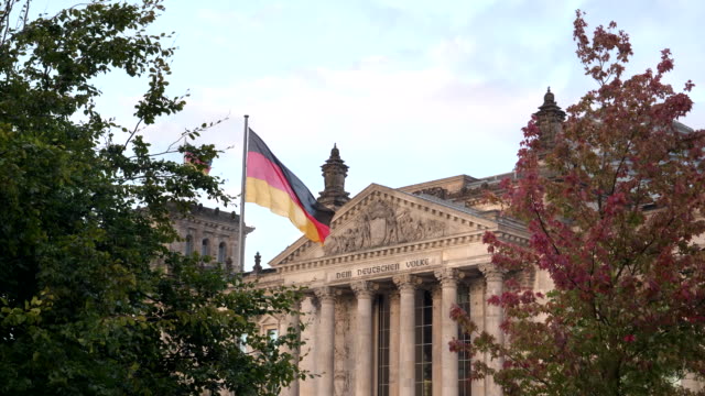 Reichstag-und-deutsche-Flagge,-umrahmt-von-Bäumen-in-Berlin,-Deutschland