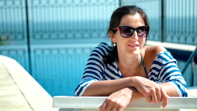 Schöne-Europäerin-in-Sonnenbrille-auf-Liegestuhl-liegend-mit-Arme-gekreuzt-genießen-Sonne