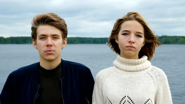 Portrait-of-two-teenagers,-a-guy-and-a-girl,-against-the-background-of-a-river-and-forest.