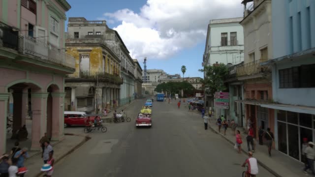 row-of-classic-1950's-American-Vintage-Convertible-cars-driving-on-street-old-Havana,-Cuba