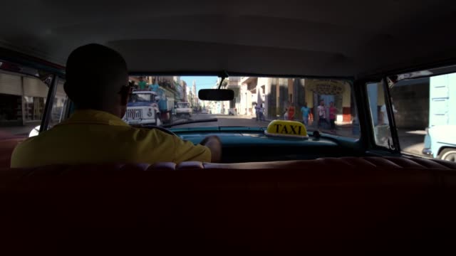 Taxista-en-vintage-coche-clásico-americano-de-1950-en-la-famosa-calle-en-el-barrio-de-la-Habana-Vieja,-Cuba