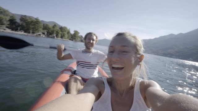 Joven-pareja-en-vacaciones-de-verano-disfrutando-de-canoa-en-el-lago-en-las-montañas.-Gente-de-viaje-divertido-concepto-de-vacaciones.-Tecnología-y-juventud-cultura-selfie---4K