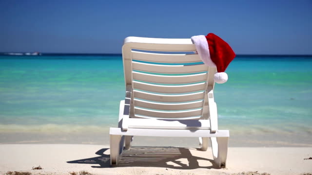 Santa-Claus-Hut-auf-dem-Liegestuhl-in-der-Nähe-des-tropischen-ruhigen-Strand