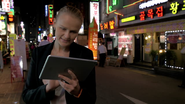 Frau-mit-Touch-Pad-auf-der-Straße-von-Seoul-in-der-Nacht,-Südkorea