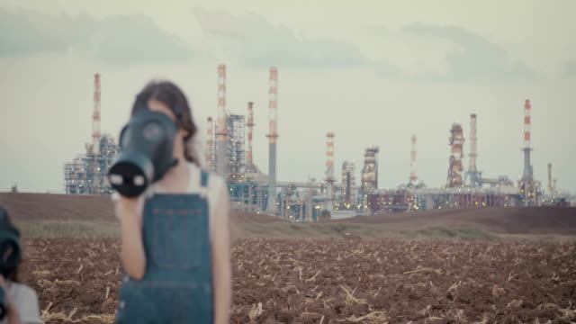 Salvar-nuestro-planeta---los-niños-con-máscaras-de-gas-cerca-de-una-refinería-de-aceite-grande