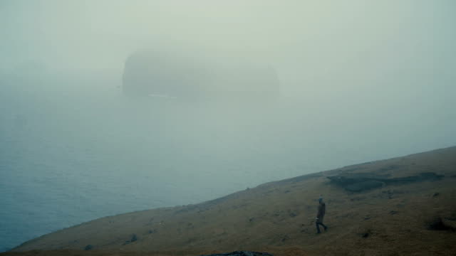 Mujer-joven-caminando-por-el-campo-en-la-orilla-de-la-mar-y-el-pensamiento,-explorando-la-naturaleza-de-Islandia