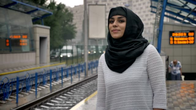 Junge-muslimische-Frau-Hijab-wartet-n-Bahnhof-Zug,-regnen,-Religion-Konzept,-städtebauliche-Konzept.-Wetter-Konzept