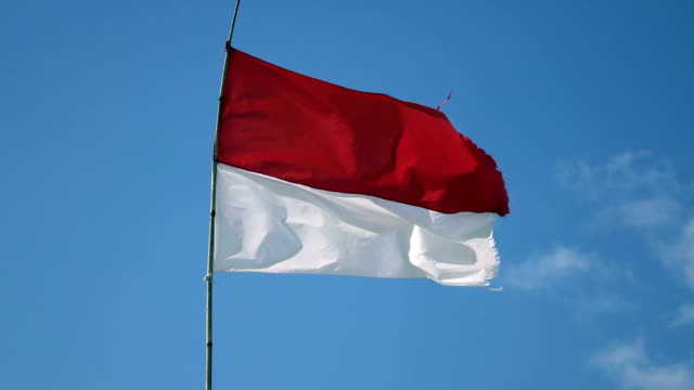 La-bandera-de-Indonesia-se-convierte-en-viento-contra-el-fondo-de-cielo-azul