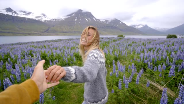 Sígueme-a-Islandia,-novia-hacia-hombre-de-campo-altramuz-de-flor-cerca-del-lago-y-las-montañas-personas-viajan-concepto---4K-video