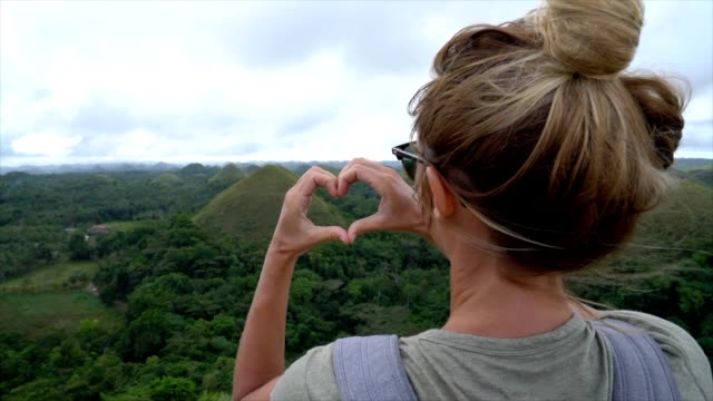 SLOW-MOTION-Mädchen-Reisen-macht-Herz-auf-Chocolate-Hills-auf-Bohol,-Philippinen