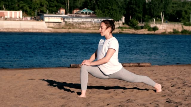 Woman-stretching-yoga-on-the-beach-by-the-river-in-the-city.-Beautiful-view.