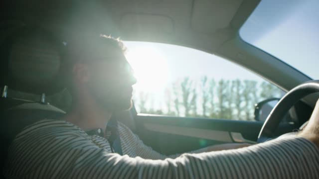 hombre-solo-es-conducir-automóvil-en-campo-en-día-soleado,-usa-gafas-de-sol,-con-volante,-inclinación-vista