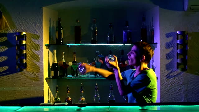 Young-bartender-making-tricks-with-two-glasses-standing-behind-the-bar,-slow-motion