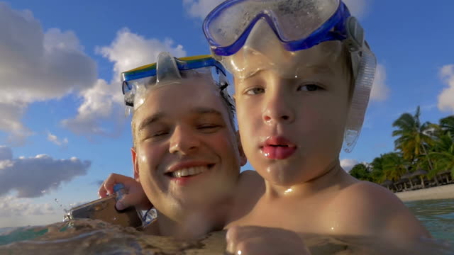 Vista-de-la-cámara-lenta-de-feliz-joven-padre-con-hijo-en-el-agua-con-máscaras-de-snorkel,-Port-Louis,-Isla-Mauricio