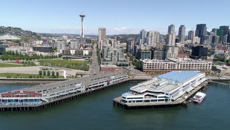 Aerial-of-Seattle,-Washington-Tourist-Attraction-the-Waterfront-Piers-with-World-Famous-Landmark-in-City-Skyline