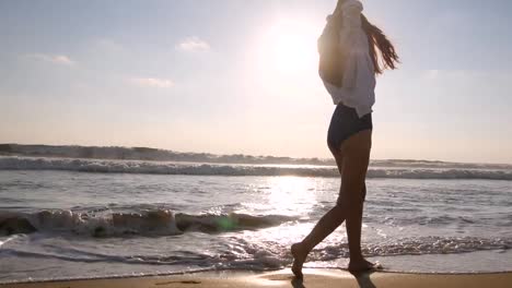 Happy-woman-walking-and-spinning-on-the-beach-near-the-ocean.-Young-beautiful-girl-enjoying-life-and-having-fun-at-sea-shore.-Summer-vacation-or-holiday.-Nature-landscape-at-background