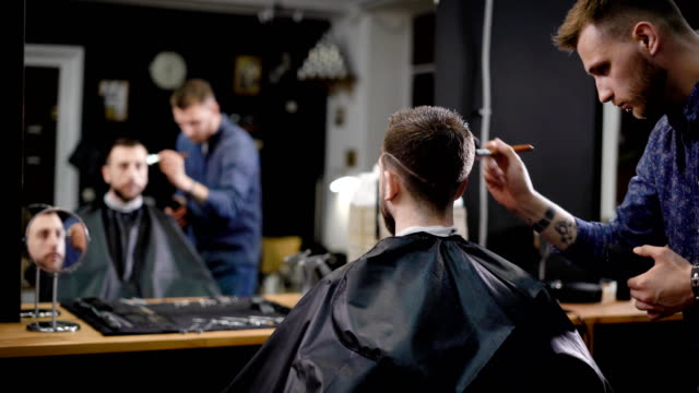 Barbero-y-el-cliente-masculino.-Peluqueria-utiliza-cepillo-al-cliente-limpio-de-pelo-cortado.-Tienda-de-peluquero