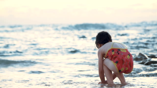 Kleine-Mädchen-spielen-am-Strand-im-Wasser-während-Sonnenuntergang-Stunde