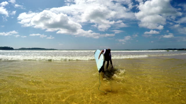 4K-Aufnahmen-von-laufen-in-Richtung-Meer-mit-einem-Brett-surfer