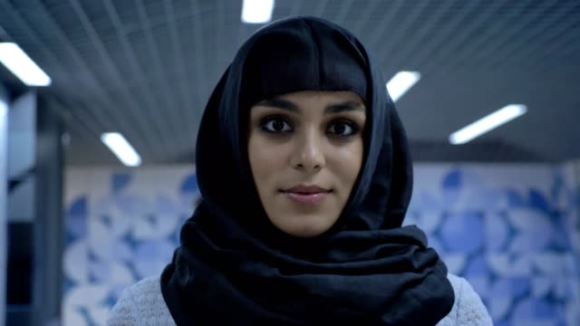 Joven-encantadora-mujer-musulmana-en-hiyab-está-de-pie-en-el-paso-subterráneo,-mirando-a-cámara,-concepto-de-religión