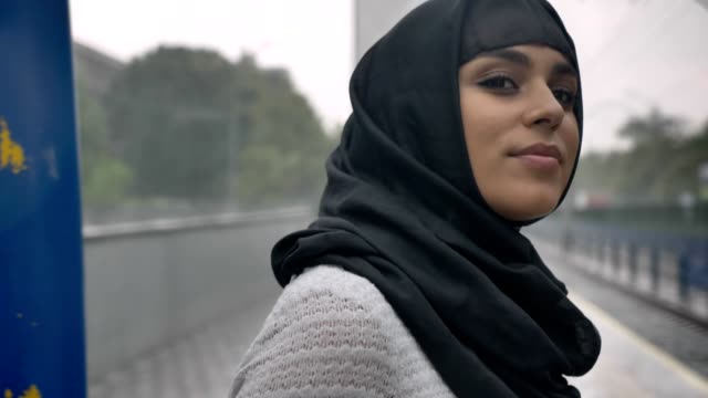Junge-muslimische-Frau-Hijab-wartet-auf-den-Zug-am-Bahnhof,-regnen,-Religion-Konzept,-städtebauliche-Konzept.-Wetter-Konzept