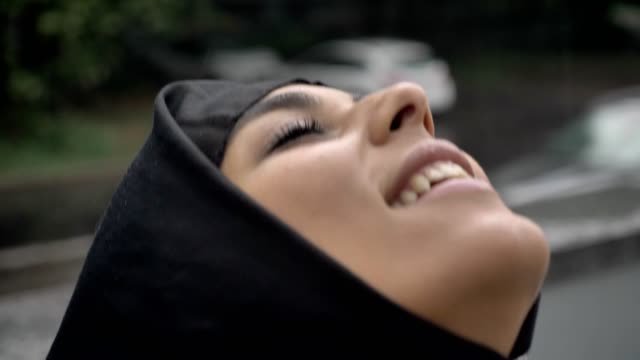 Junge-muslimische-Frau-Hijab-erfreut-sich-Regen,-Religion-Konzept,-Wetter-Konzept,-Seitenansicht