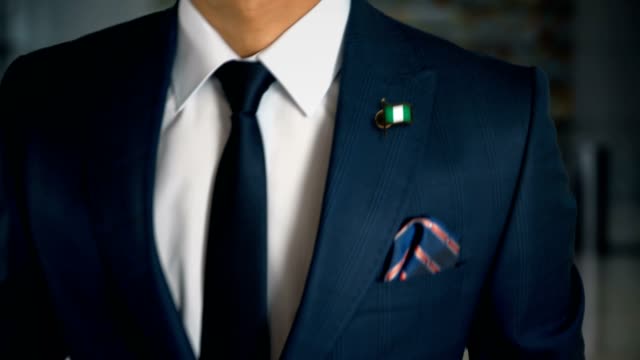 Geschäftsmann-zu-Fuß-in-Richtung-Kamera-mit-Land-Flagge-Pin---Nigeria