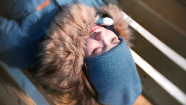 Junge-Frau-im-Park-auf-einer-Bank-im-Winter-schläft.-Close-up-Gesicht.