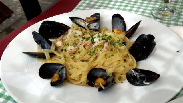 Traditional-mediterranean-pasta-with-mussels-and-seafood-on-a-traditional-Mediterranean-plate-garnished-with-summer-vegetables-and-fruits---greece,-croatia,-italy,-montenegro,-squid.