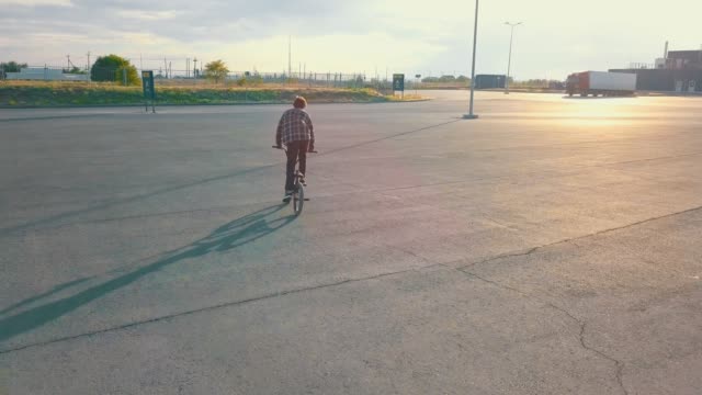 fliegende-Kamera-Junge-männliche-Jugendliche-Reiter-auf-dem-bmx-Rad-auf-der-leeren-städtischen-Stelle,-die-keine-Menschen-asphalt