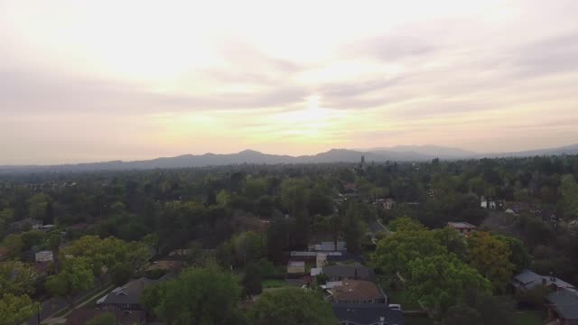 Vista-aérea-del-barrio-y-montañas-durante-la-puesta-de-sol-en-California