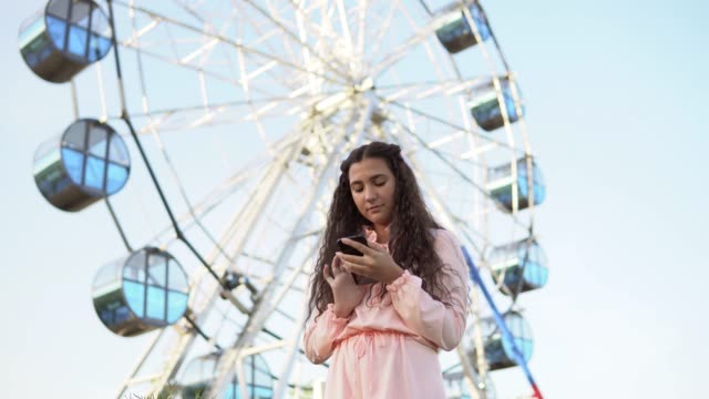 The-girl-is-using-a-smartphone-standing-near-the-Ferris-wheel-.4K