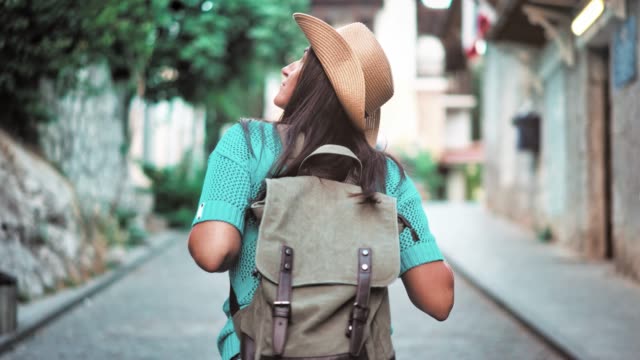 Mujer-de-mochila-de-excursionista-activo-posterior-vista-en-sombrero-caminando-por-la-calle-estrecha-de-la-acogedora-ciudad-europea