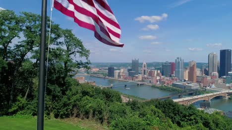 Rising-Aerial-View-of-American-Flag-and-Pittsburgh-Skyline