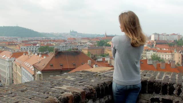 schlanke-blonde-Frau-ist-Panorama-Blick-auf-die-Stadt-Prag-in-windigen-Wetter-bewundern.