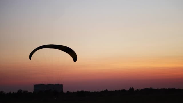 The-pilot-on-the-paraglider-comes-to-land-in-the-field-at-sunset