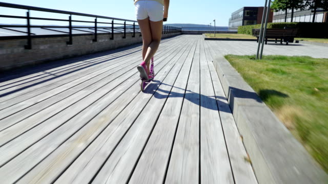 Teenage-girl-riding-a-Kick-Scooter-on-the-wooden-promenade.