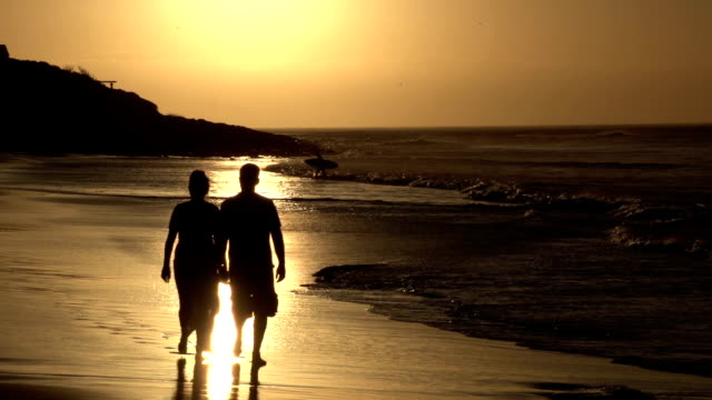 Couple-enjoying-romantic-walk-along-the-beach-in-silhouette,-Cape-Town,South-Africa