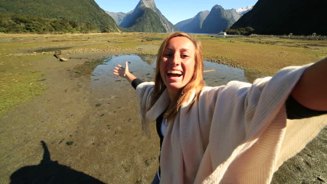 Young-woman-takes-selfie-portrait-on-mountain-background