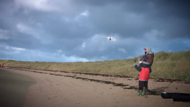 4k-Shot-of-two-Boys-Flying-the-Drone-on-the-beach-in-Ireland
