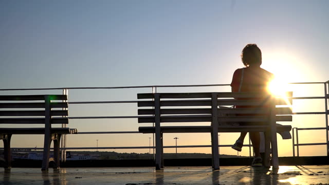 Silhouette-of-a-senior-woman-sitting-on-a-cruise-ship-yacht-deck-at-sunset