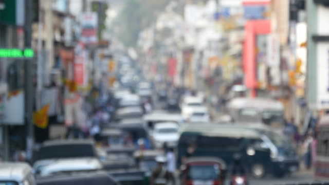 Blurred-unrecognizable-people-are-walking-around-city-center.-Cars-drive-on-roads-in-the-town.-Out-of-focus-is-backdrop-of-bustling-big-city-with-busy-traffic