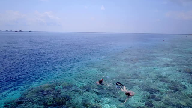 v04065-vista-aérea-de-drone-volando-de-Maldivas-playa-2-personas-pareja-joven-hombre-mujer-snorkel-natación-buceo-en-la-isla-de-paraíso-tropical-soleado-con-cielo-azul-aqua-agua-mar-4k