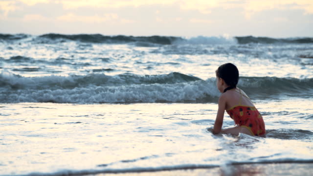 Little-girl-playing-on-the-beach-in-the-water-during-sunset-hour