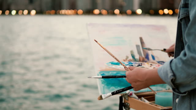 Nahaufnahme-der-jungen-Frau-hält-den-Pinsel-und-zeichnen-das-Bild-am-Ufer-des-Michigan-Sees,-Chicago,-Amerika